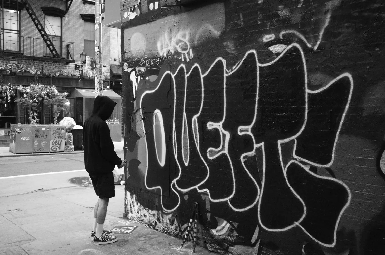 Graffiti QUEFT en una pared de Nueva York, con el autor de pie frente a ella